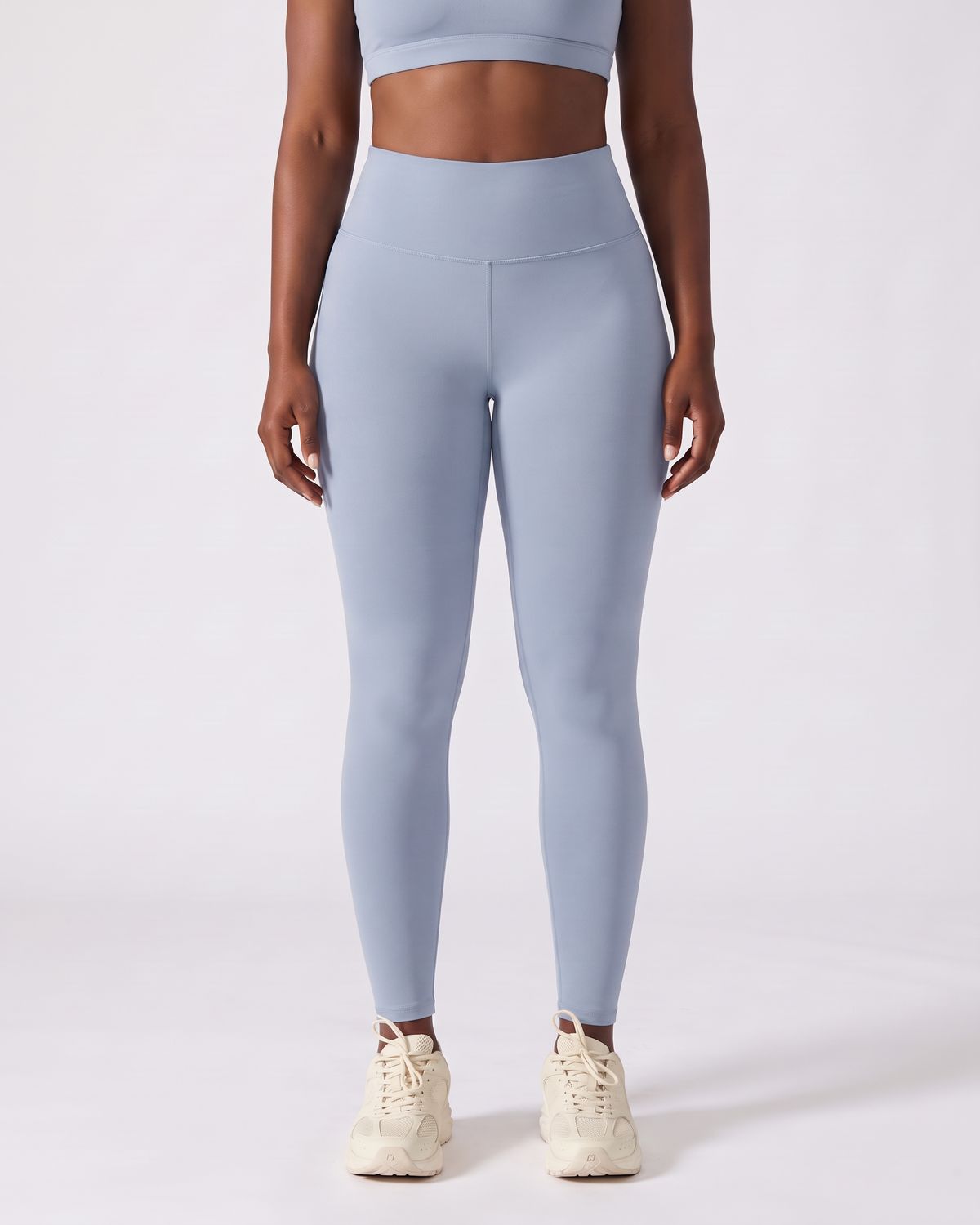 Legging AIKISculpt bleu porté sur fond clair, vue de face, de la poitrine aux pieds