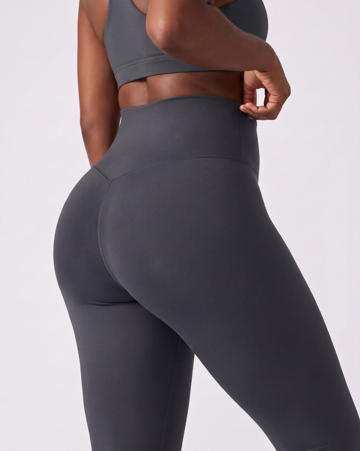 Legging AIKISculpt gris porté sur fond clair, gros plan de dos sur la ceinture large et le galbe des fessiers