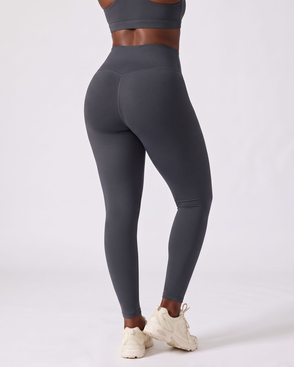 Legging AIKISculpt gris porté sur fond clair, vu de dos, ceinture en V au dos et fessiers galbés