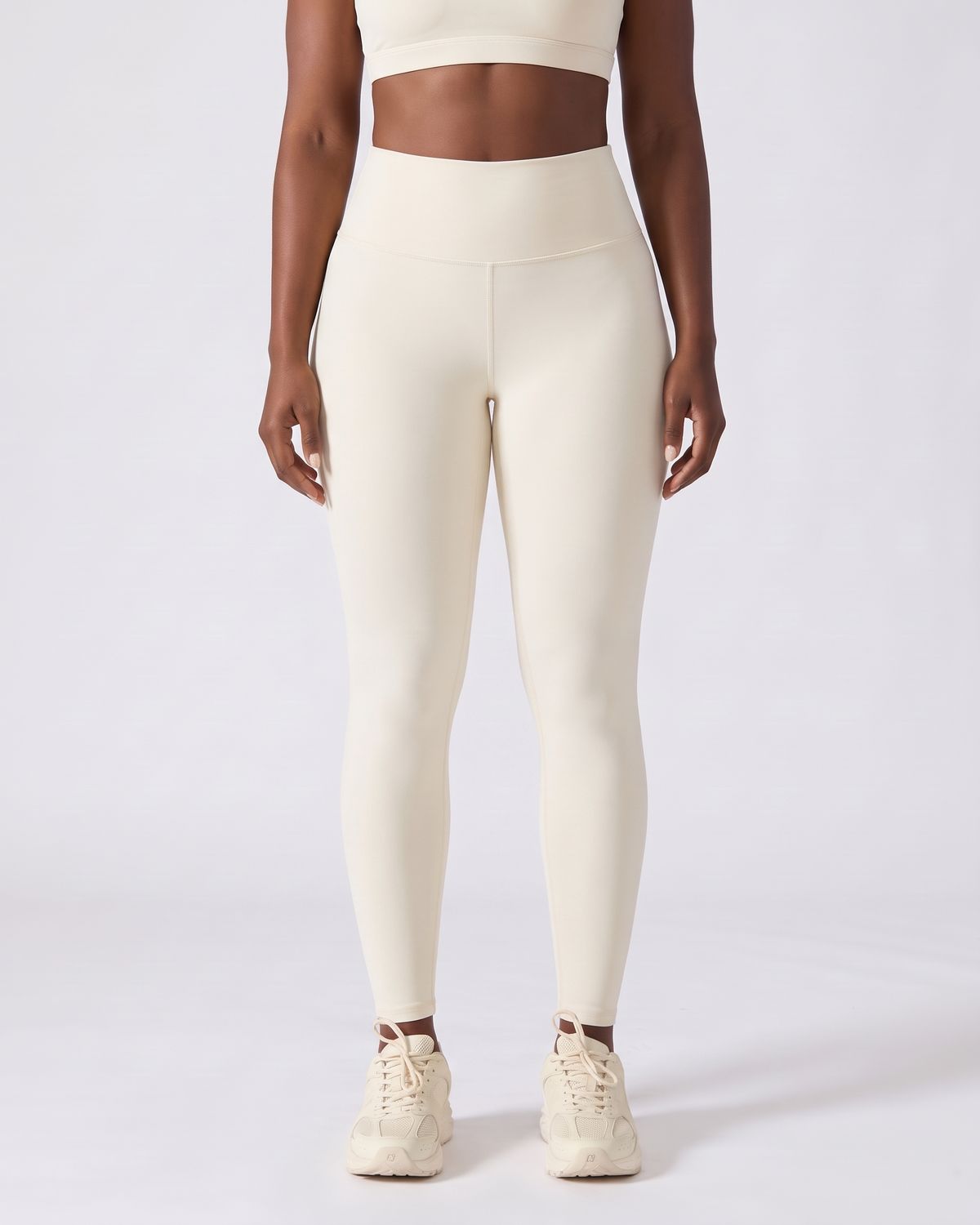 Legging AIKISculpt ivoire porté sur fond clair, vue de face, de la poitrine aux pieds