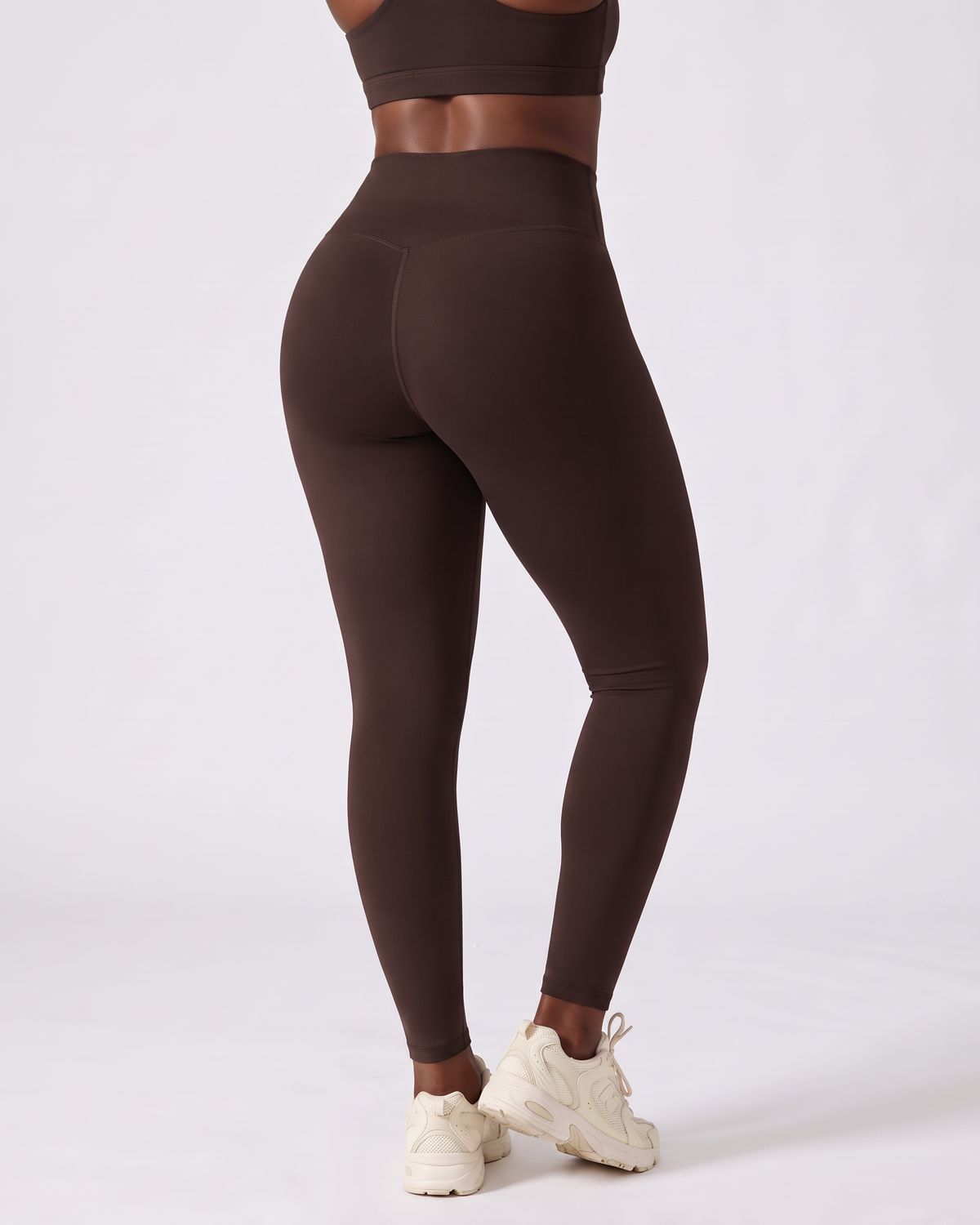 Legging AIKISculpt marron porté sur fond clair, vu de dos, ceinture en V au dos et fessiers galbés