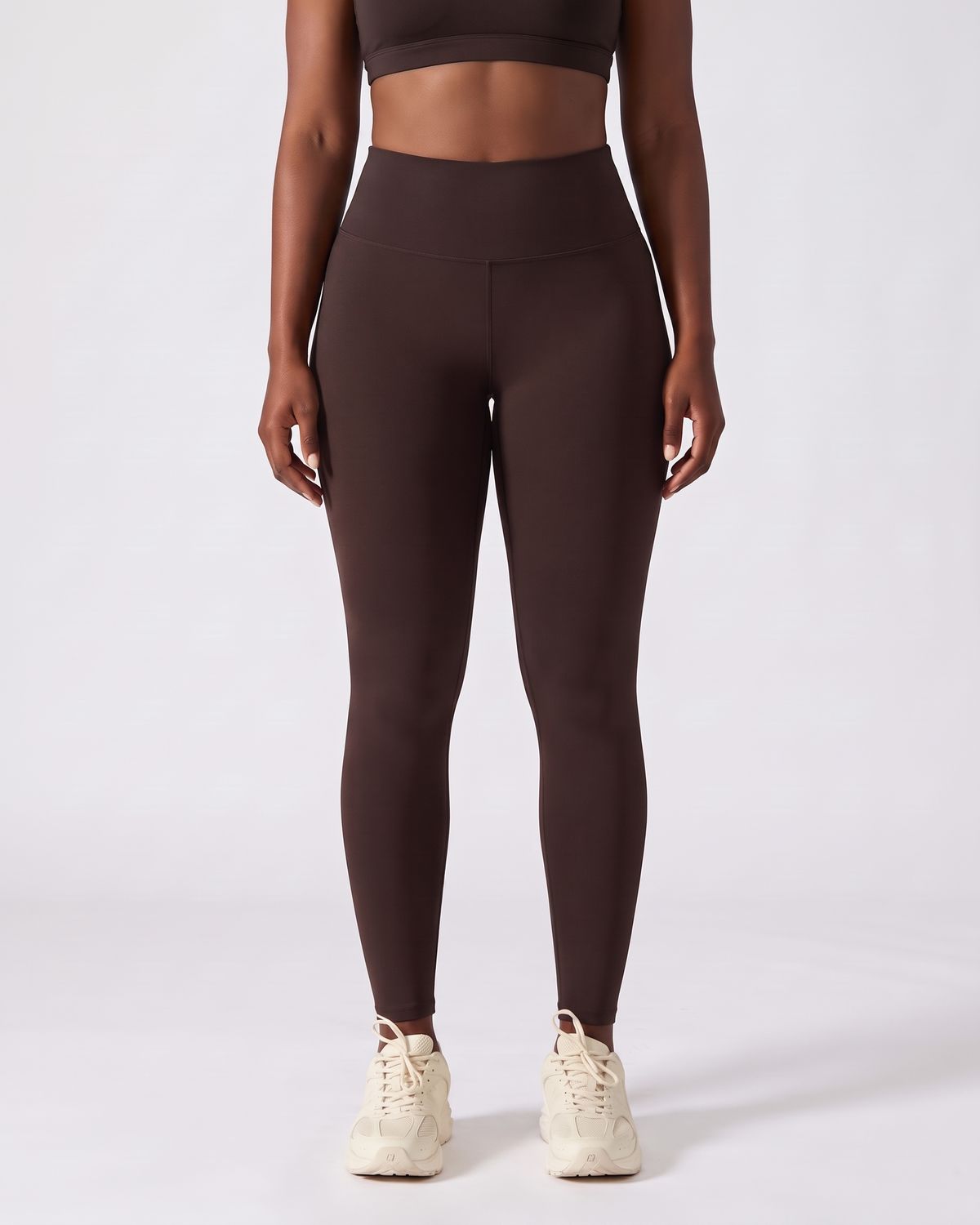 Legging AIKISculpt marron porté sur fond clair, vue de face, de la poitrine aux pieds