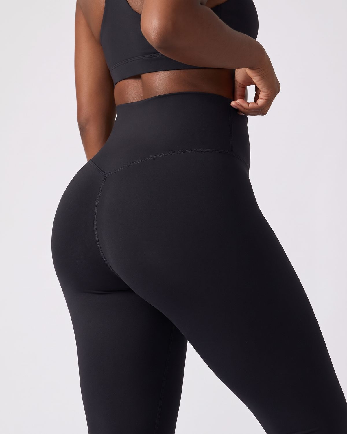 Legging AIKISculpt noir porté sur fond clair, gros plan de dos sur la ceinture large et le galbe des fessiers