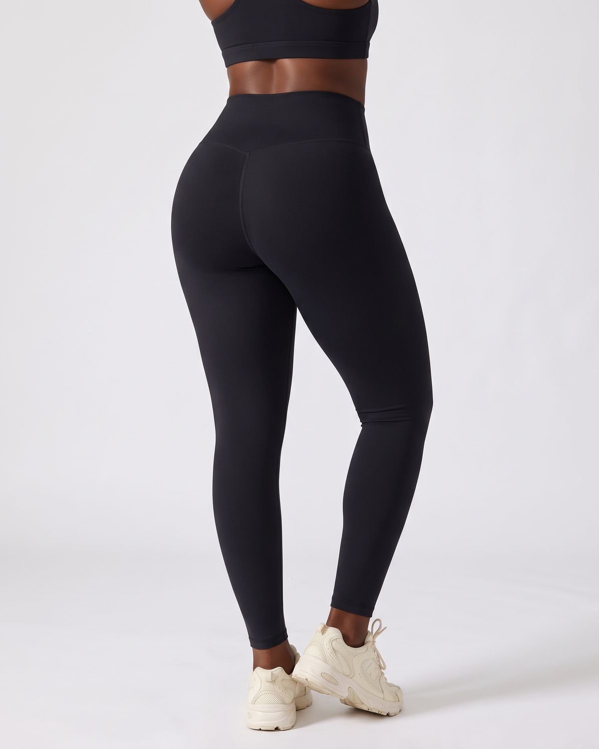 Legging AIKISculpt noir porté sur fond clair, vu de dos, ceinture en V au dos et fessiers galbés