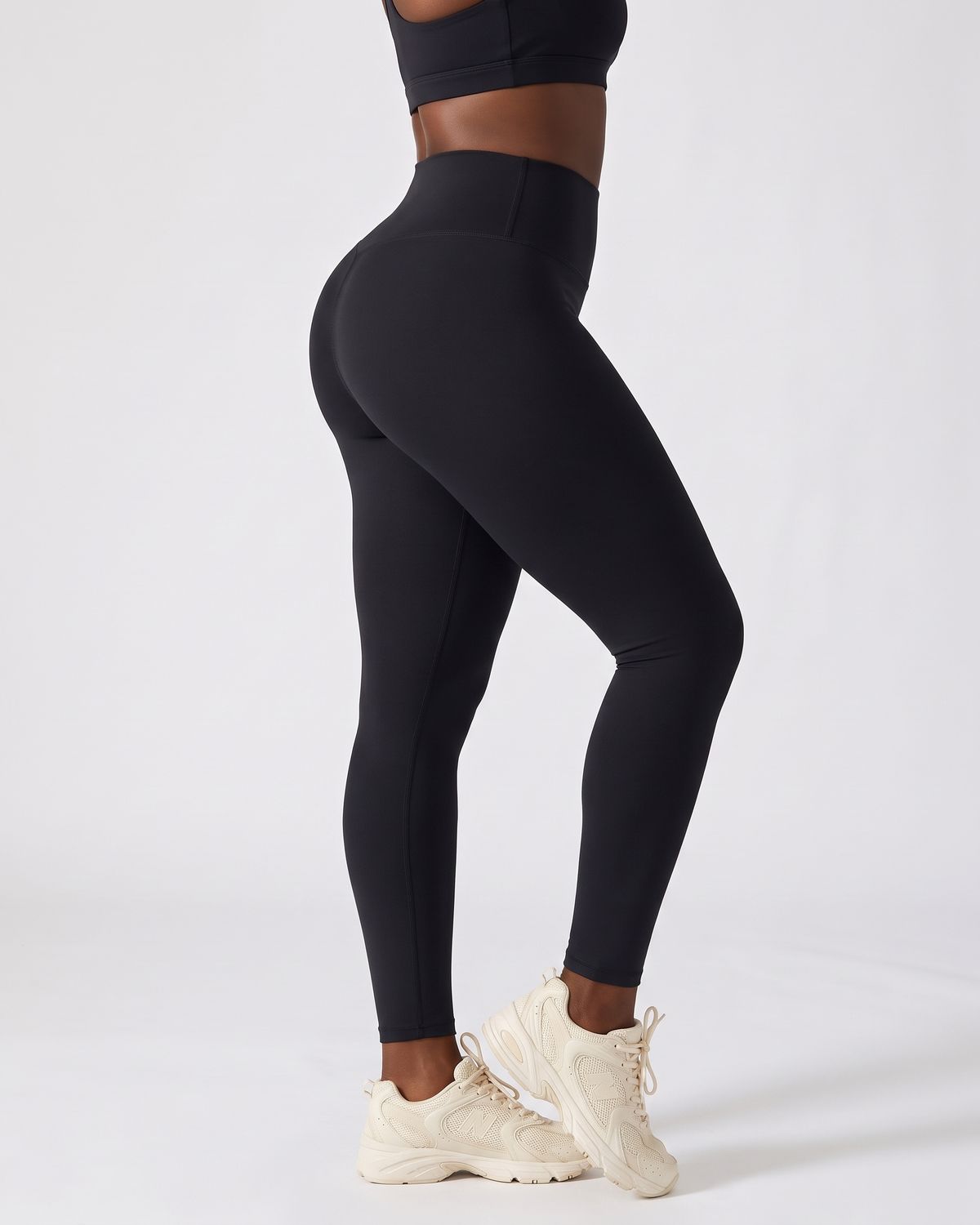 Legging AIKISculpt noir porté sur fond clair, vu de trois quarts dos, de la poitrine aux pieds