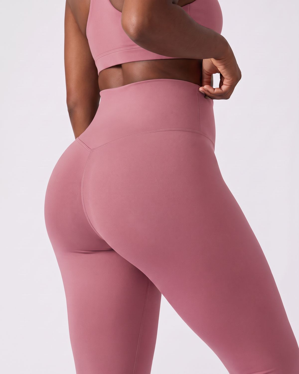 Legging AIKISculpt rose porté sur fond clair, gros plan de dos sur la ceinture large et le galbe des fessiers