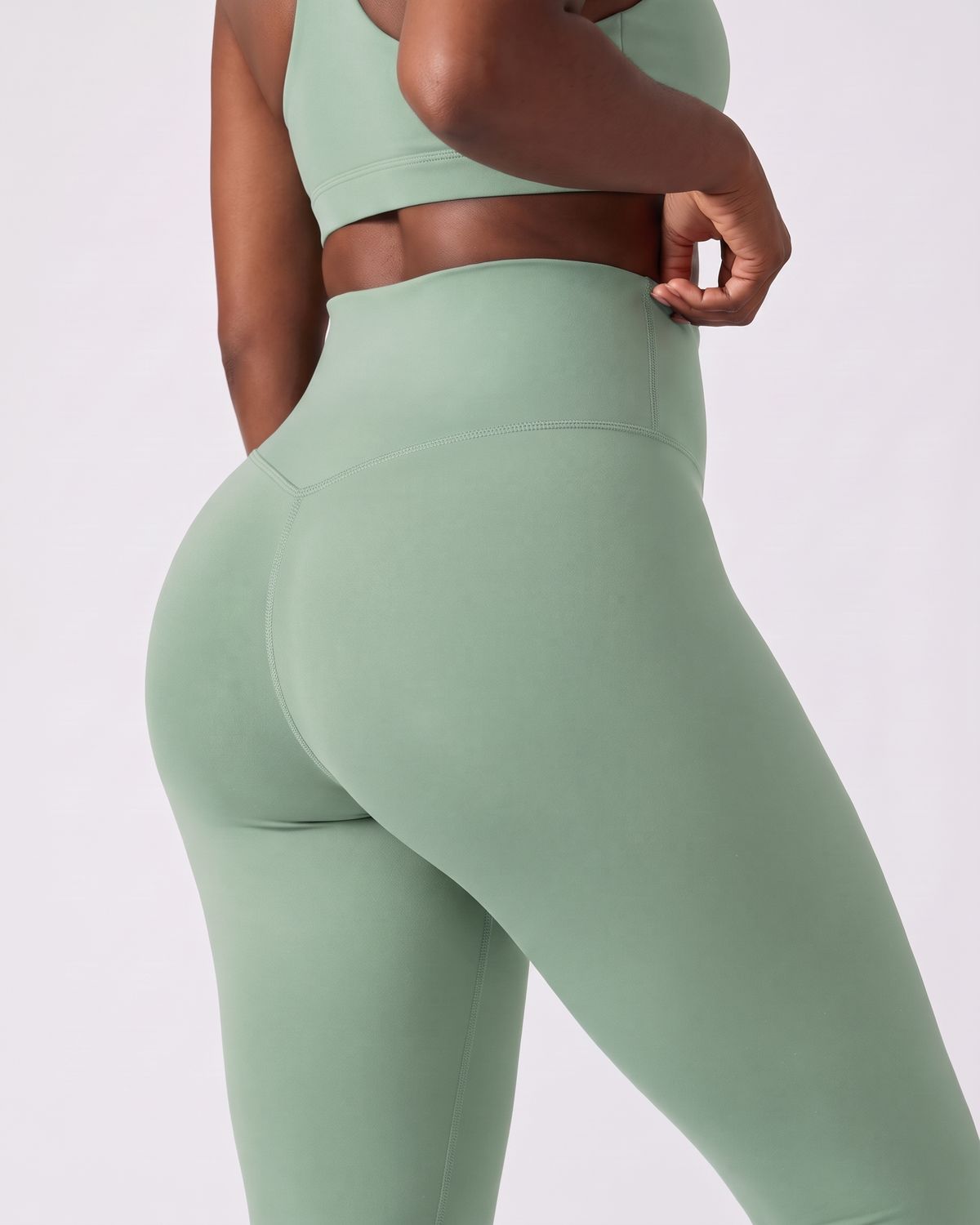 Legging AIKISculpt sauge porté sur fond clair, gros plan de dos sur la ceinture large et le galbe des fessiers