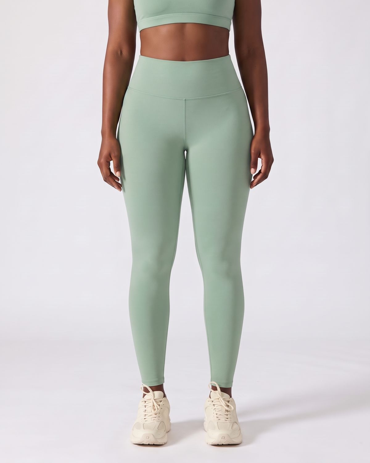 Legging AIKISculpt sauge porté sur fond clair, vue de face, de la poitrine aux pieds