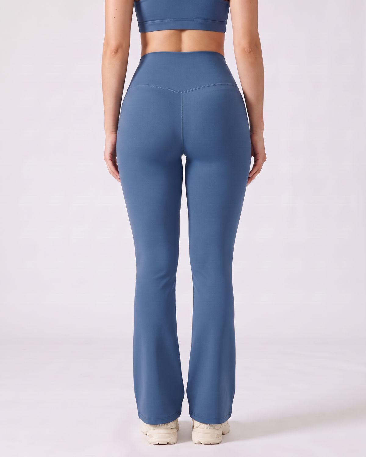 Legging Flare AIKISculpt bleu porté sur fond clair, vu de dos, ceinture en V au dos