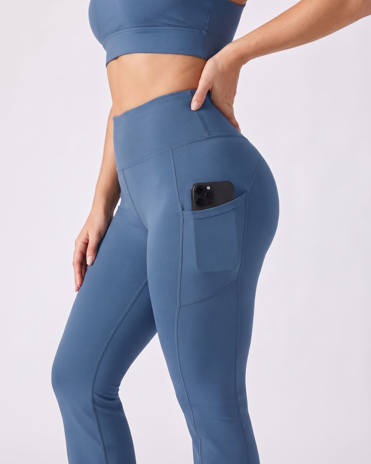 Legging Flare AIKISculpt bleu porté sur fond clair, gros plan sur la poche latérale avec un téléphone glissé dedans