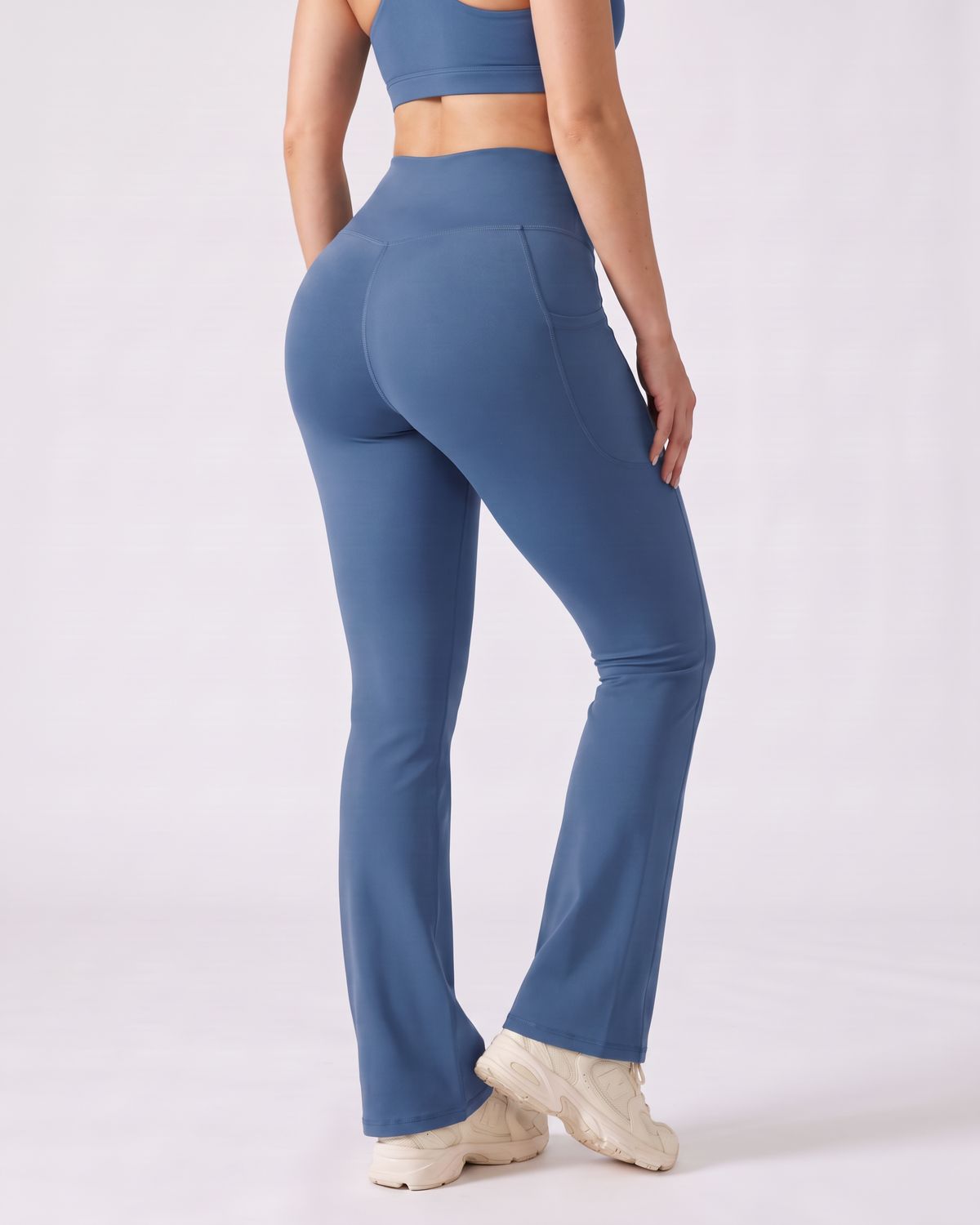 Legging Flare AIKISculpt bleu porté sur fond clair, vu de trois quarts dos, de la poitrine aux pieds