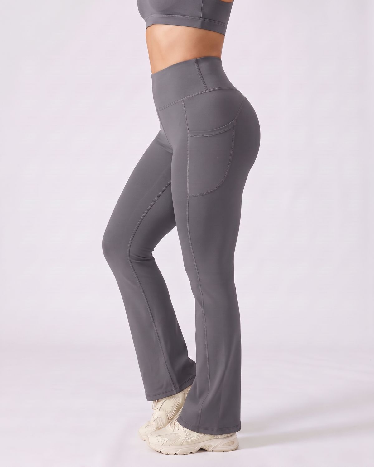 Legging Flare AIKISculpt gris porté sur fond clair, vue de profil, poche latérale et évasé à partir du genou