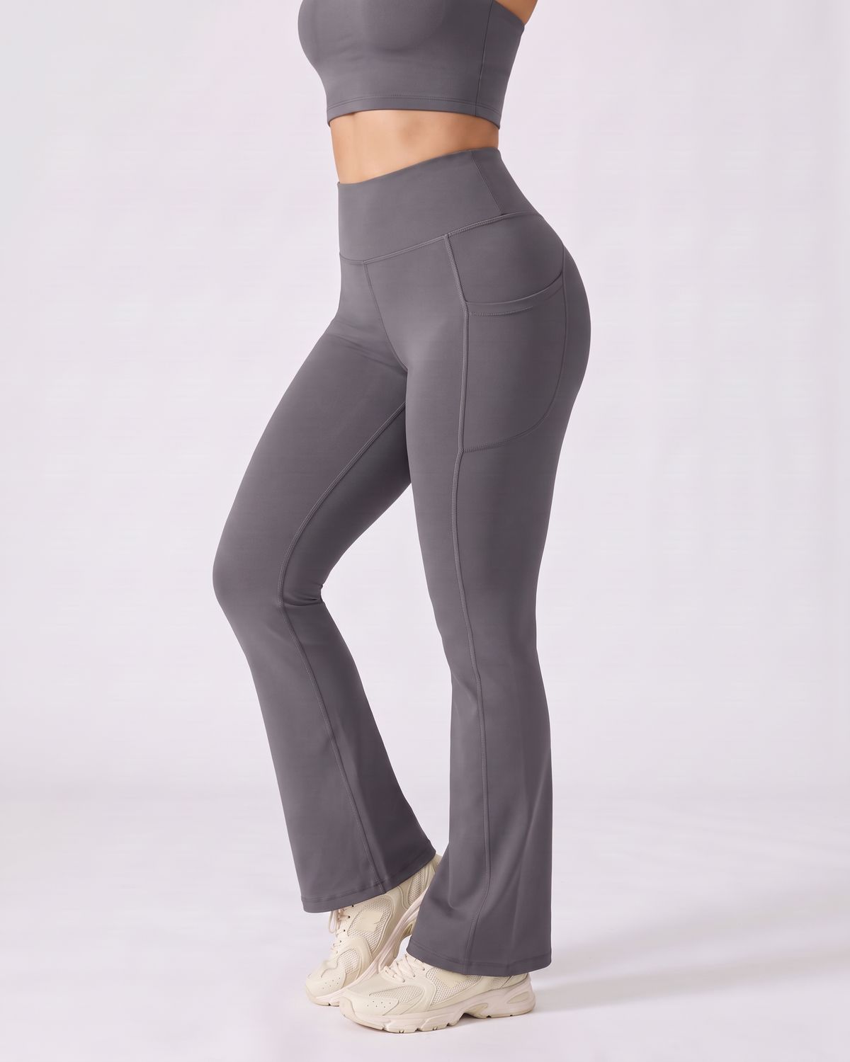 Legging Flare AIKISculpt gris porté, vu de trois quarts sur fond clair, de la poitrine aux pieds, évasé à partir du genou