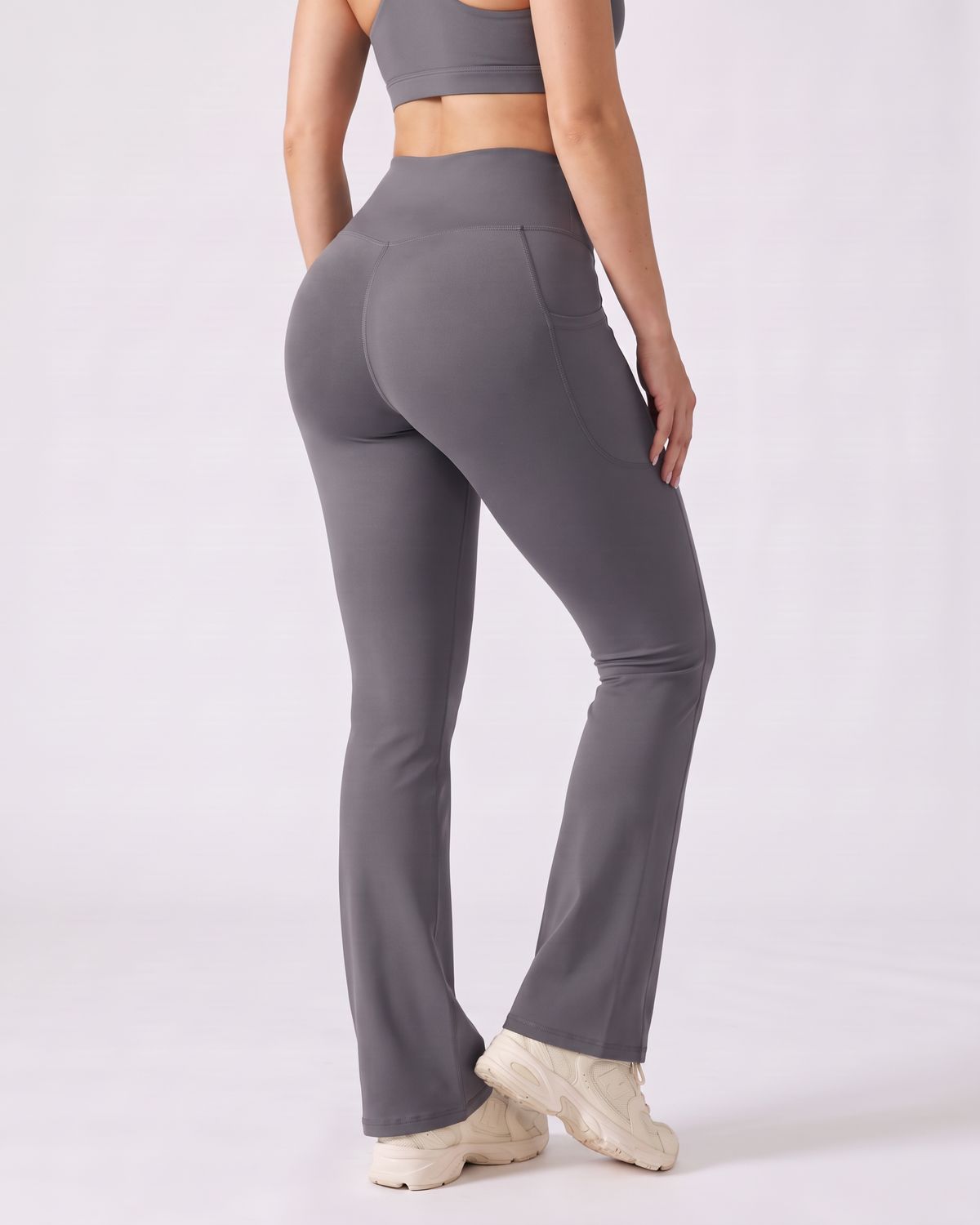 Legging Flare AIKISculpt gris porté sur fond clair, vu de trois quarts dos, de la poitrine aux pieds