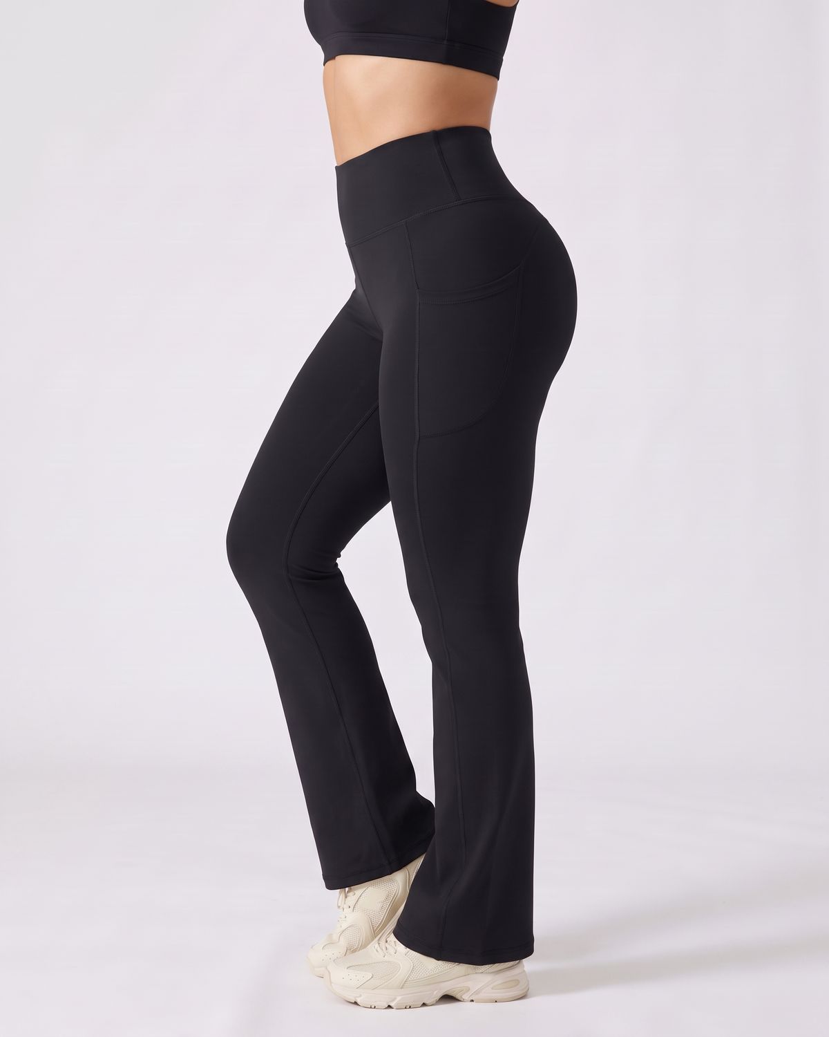 Legging Flare AIKISculpt noir porté sur fond clair, vue de profil, poche latérale et évasé à partir du genou