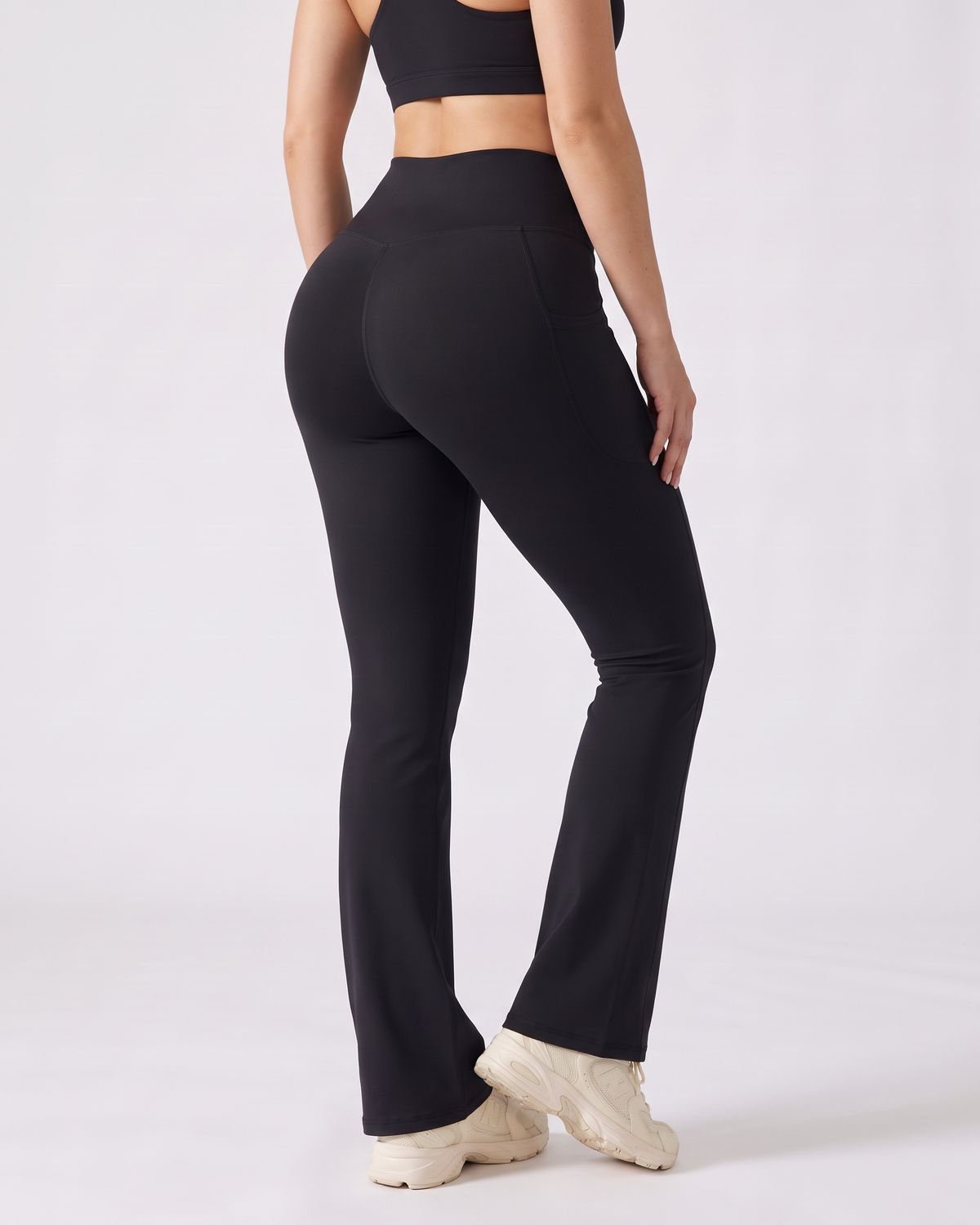 Legging Flare AIKISculpt noir porté sur fond clair, vu de trois quarts dos, de la poitrine aux pieds
