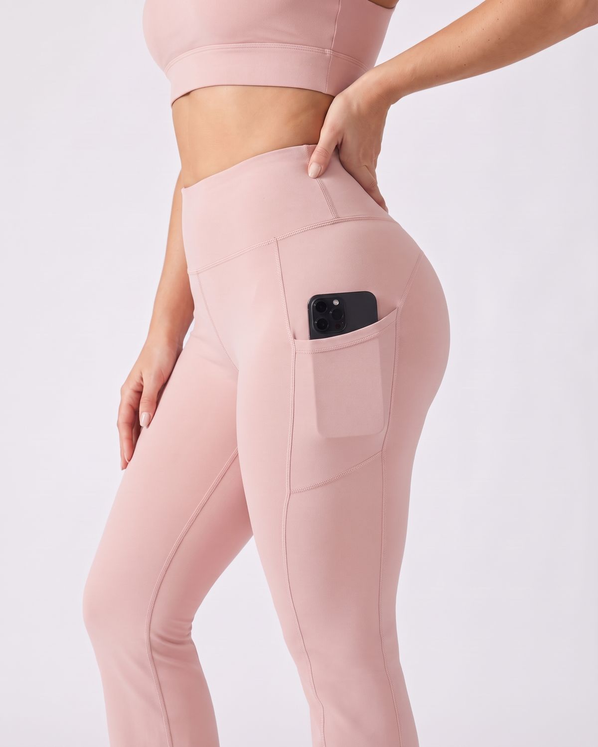 Legging Flare AIKISculpt rose porté sur fond clair, gros plan sur la poche latérale avec un téléphone glissé dedans