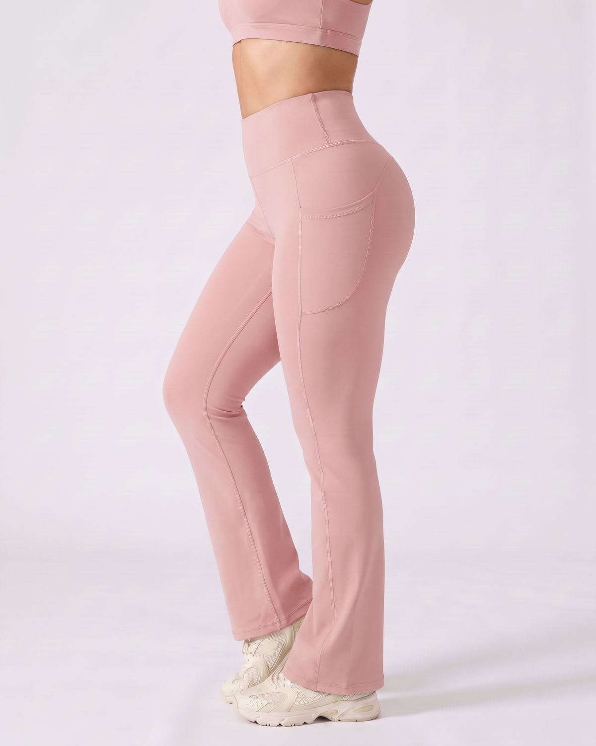 Legging Flare AIKISculpt rose porté sur fond clair, vue de profil, poche latérale et évasé à partir du genou