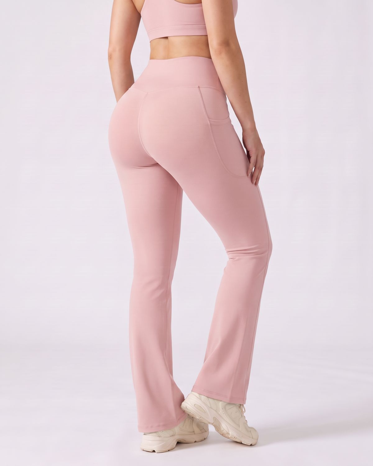 Legging Flare AIKISculpt rose porté sur fond clair, vu de trois quarts dos, de la poitrine aux pieds