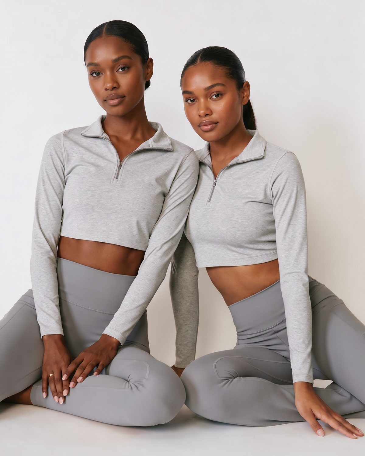 Deux femmes assises au sol en legging gris taille haute, l'une en legging AIKISculpt ajusté, l'autre en legging Flare AIKISculpt
